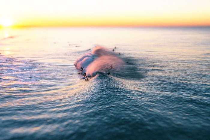 Surfers riding waves at sunset