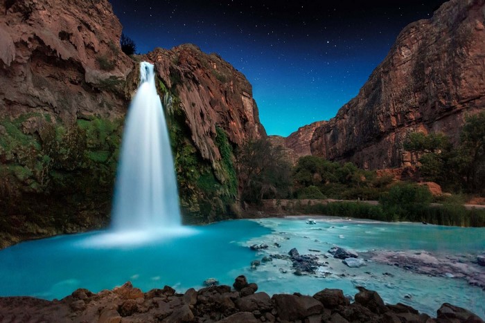 Waterfall in a canyon under a starry night sky