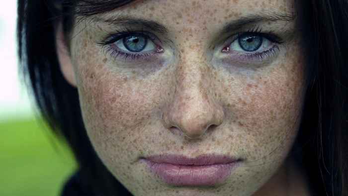 Close-up of a woman with freckles and blue eyes