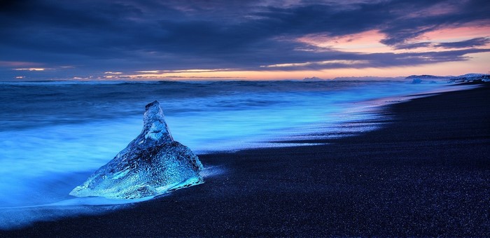 Iceberg on black sand beach at sunset, Iceland