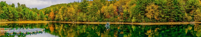 Autumn forest reflected in a calm lake with boats