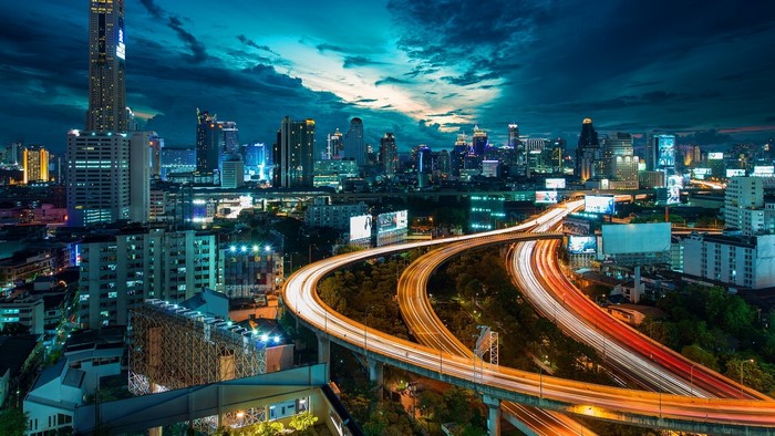 Bangkok cityscape at night with light trails on highways