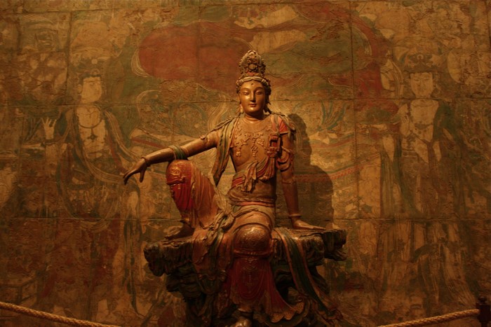 Guanyin Bodhisattva statue in front of mural