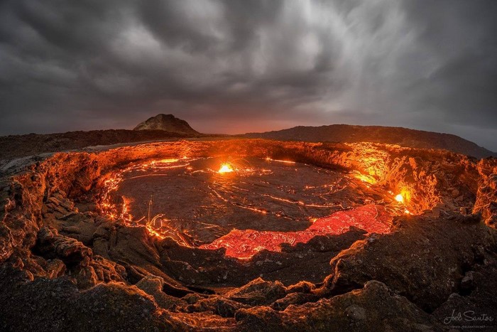 Volcano crater with lava and stormy clouds