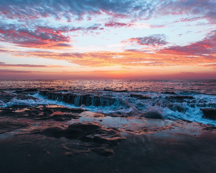 Waves crashing on rocks at sunset