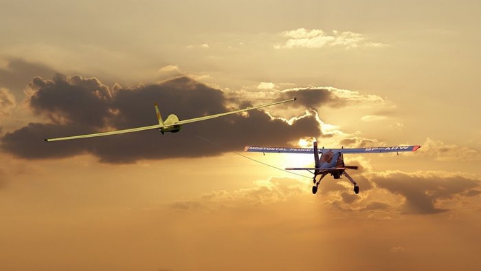 Glider towed by a small airplane at sunset