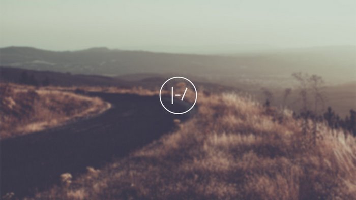 Twenty One Pilots logo on a scenic landscape
