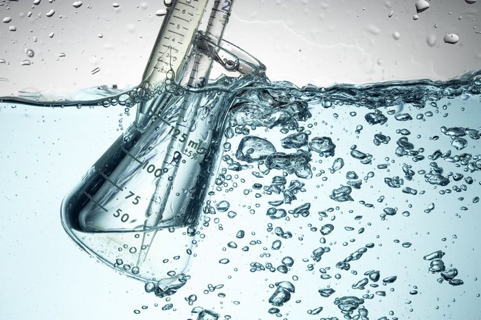 Chemistry experiment with flask and pipette in water