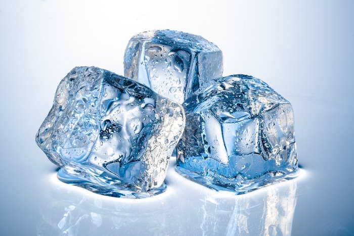 Three melting ice cubes with water drops