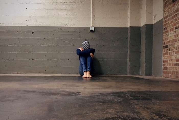Person sitting alone in a concrete room