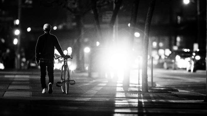 Man walking a bicycle at night