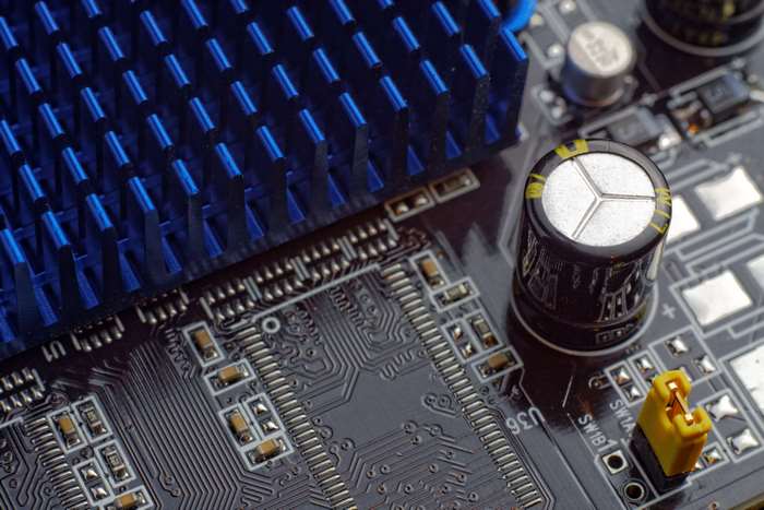 Close-up of a complex electronic circuit board with a blue heatsink and capacitor