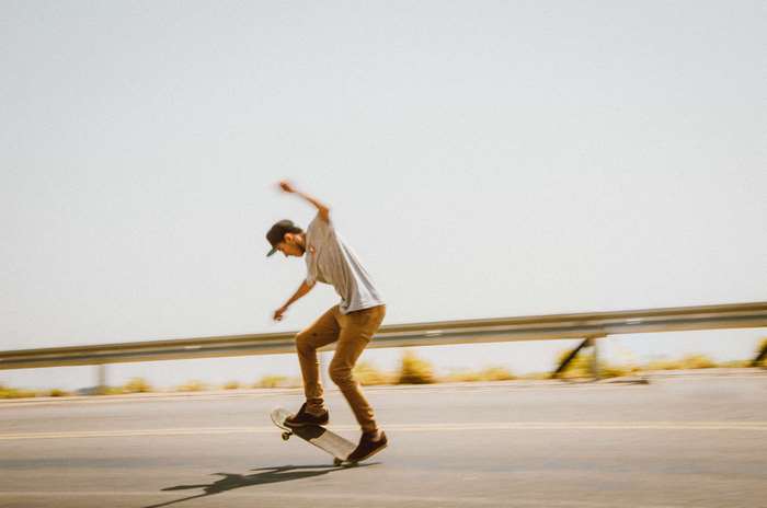 Skater performing a trick on a road with a guardrail