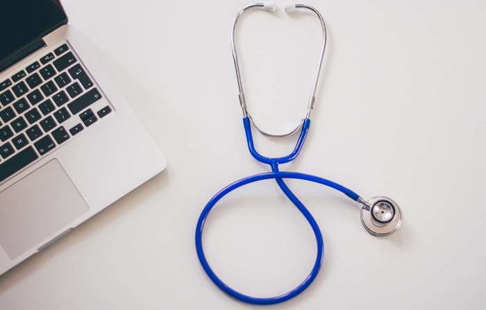 Laptop and blue stethoscope on a white desk