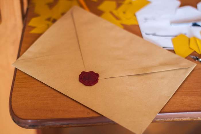 Brown envelope with red wax seal on wooden table