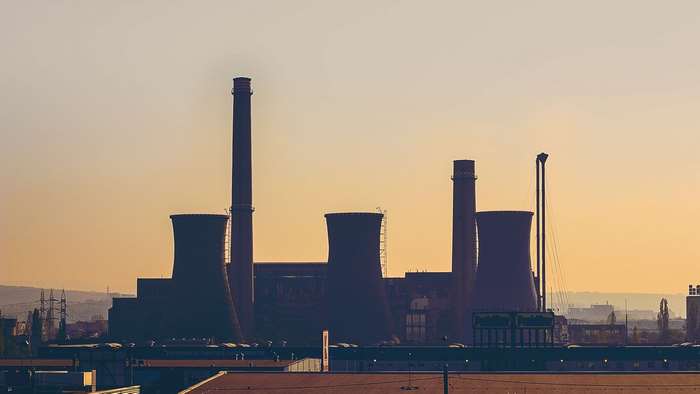 Industrial power plant cooling towers and chimneys at sunset