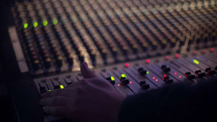 Hand on audio mixing console with lights