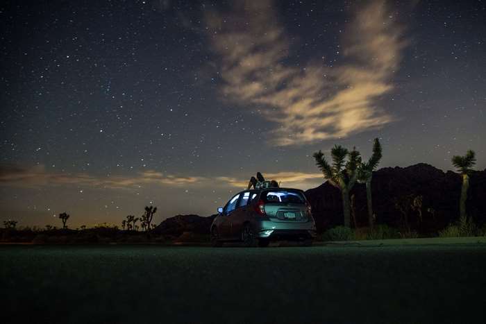 People stargazing on car roof in desert at night