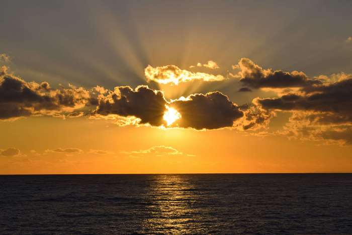 Sunset over the sea with sunbeams through clouds 4K