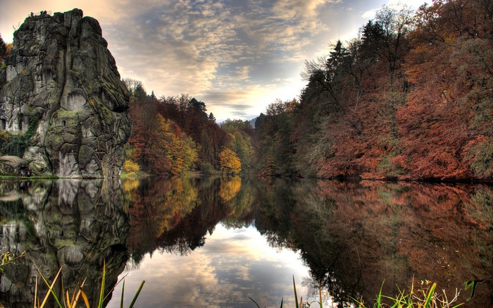 Autumn forest reflected in a lake with a large rock formation