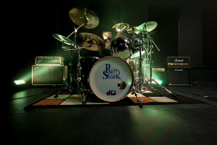 Drummer playing a drum set with Marshall amplifiers