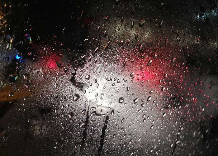 Raindrops on a car window at night with blurred lights