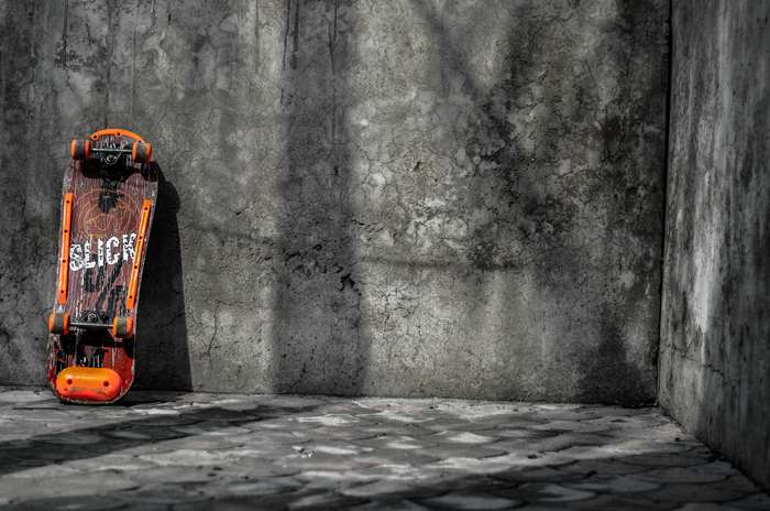 Skateboard with SLICK logo leaning on concrete wall
