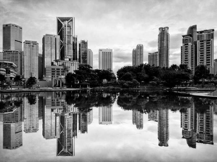 Black and white cityscape with skyscrapers reflected in a lake
