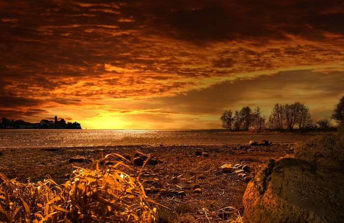 Sunset over the sea with a distant town and trees