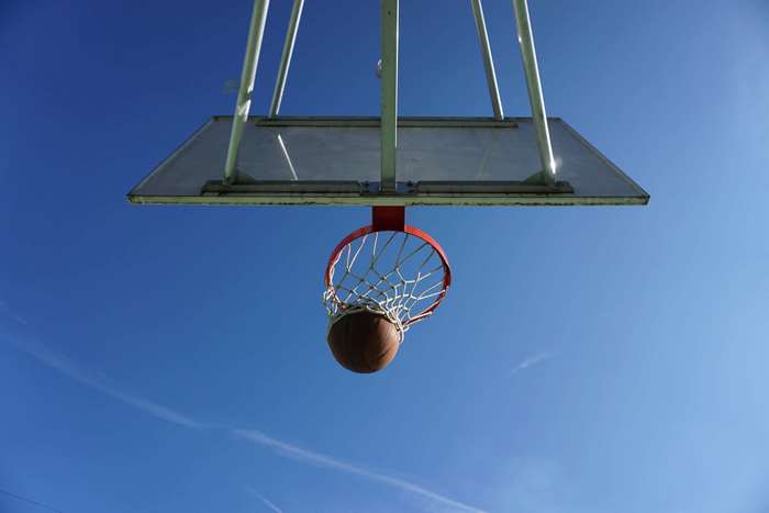 Basketball in a hoop against a blue sky