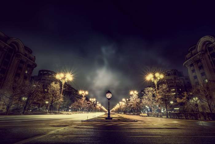 City street at night with illuminated buildings and clock