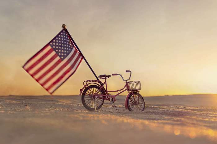 Pink bicycle with American flag on sandy beach at sunset