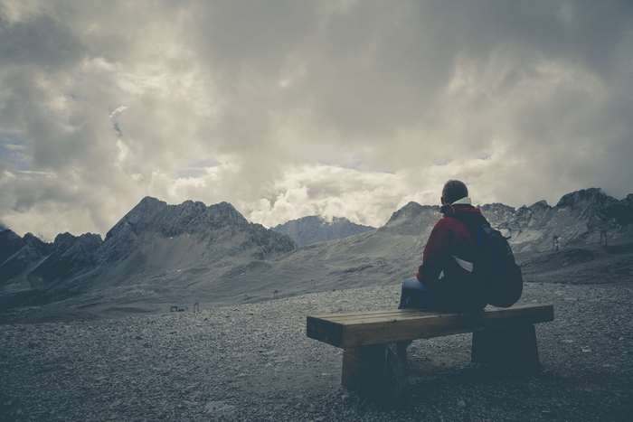 Person sitting on bench overlooking mountains
