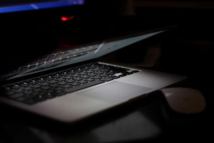 MacBook laptop with keyboard and mouse in dark