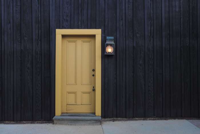 Yellow door on a dark wooden wall with a lantern