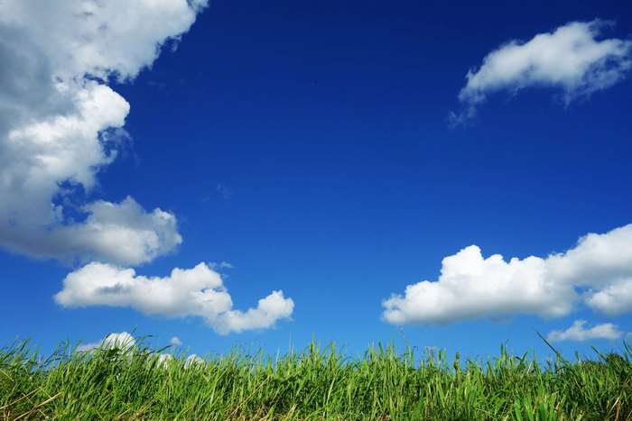 Blue sky with cumulus clouds over green grass field