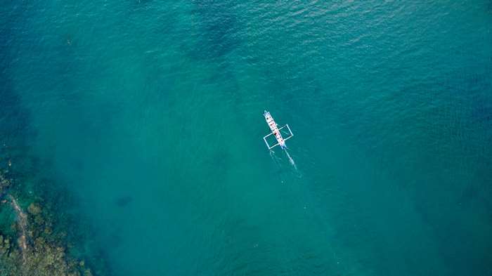 Boat sailing on turquoise ocean water from above