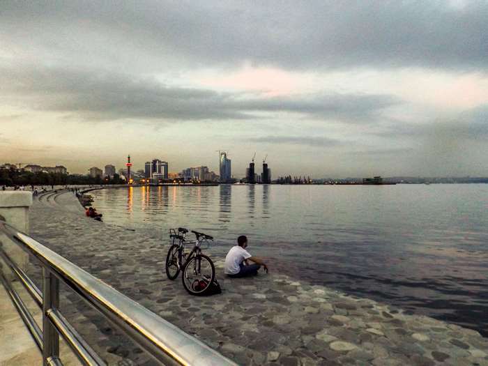 Baku cityscape with people and bicycles by the sea