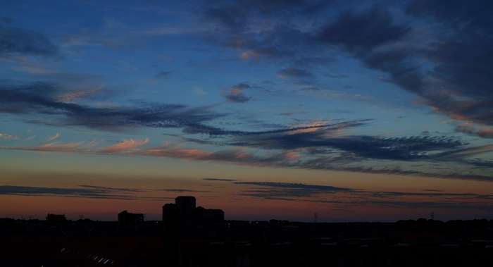 Dark clouds at sunset over a silhouetted city