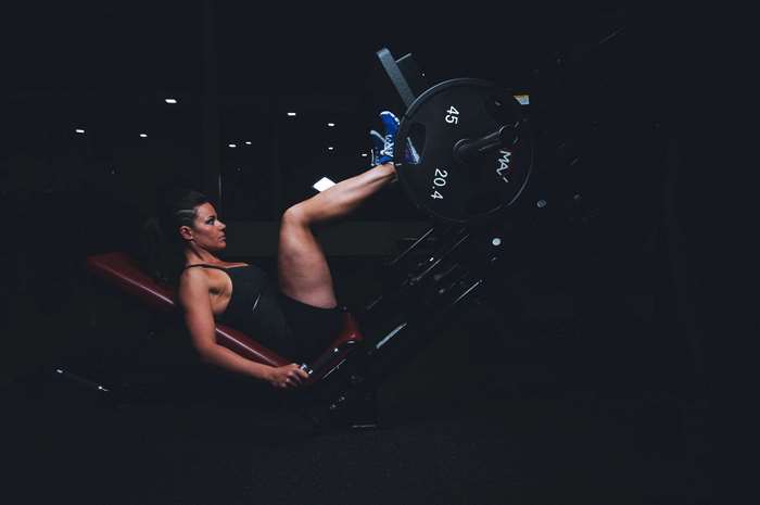 Woman Using Leg Press Machine in Dark Gym 4K