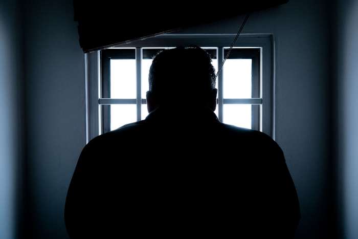 Silhouette of a man in front of a barred window