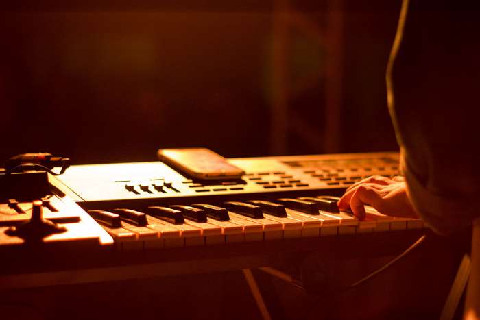 Person playing a keyboard with a phone on it