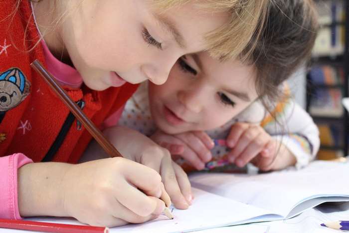 Two young girls studying and drawing with pencils