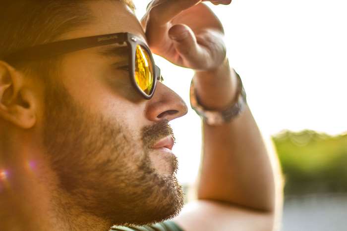 Man wearing sunglasses and shielding eyes from sun