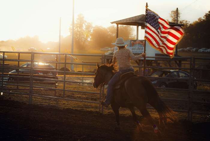 Cowgirl with American Flag at Rodeo Sunset 4K