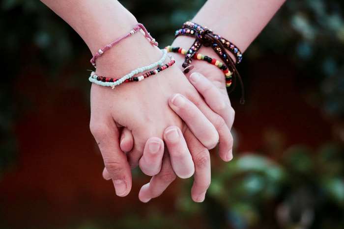Two people holding hands with bracelets