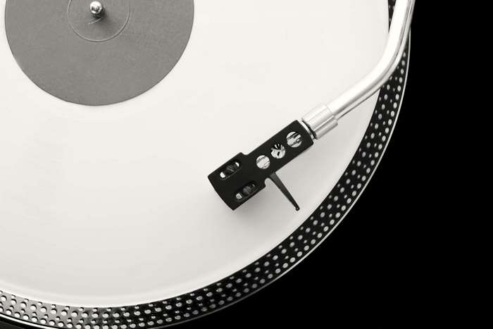 Turntable with tonearm and stylus on white vinyl record