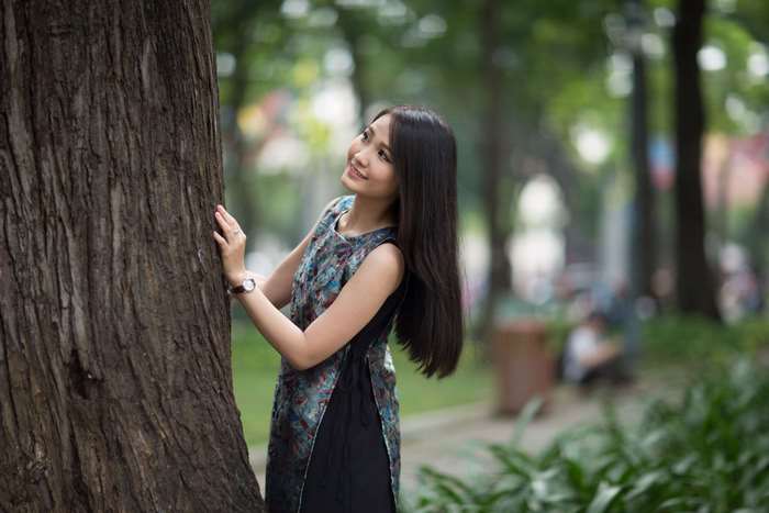 Woman in a dress posing by a tree in a park 4K