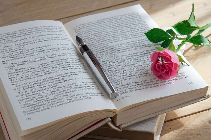 Open book with pen and rose with ring