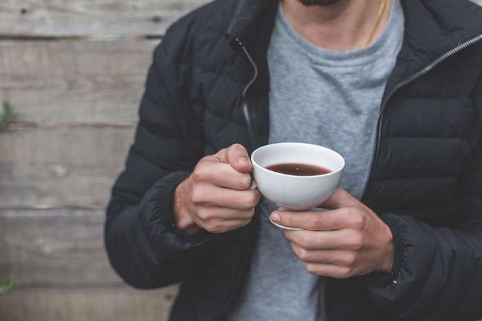Man in puffer jacket holding a cup of tea